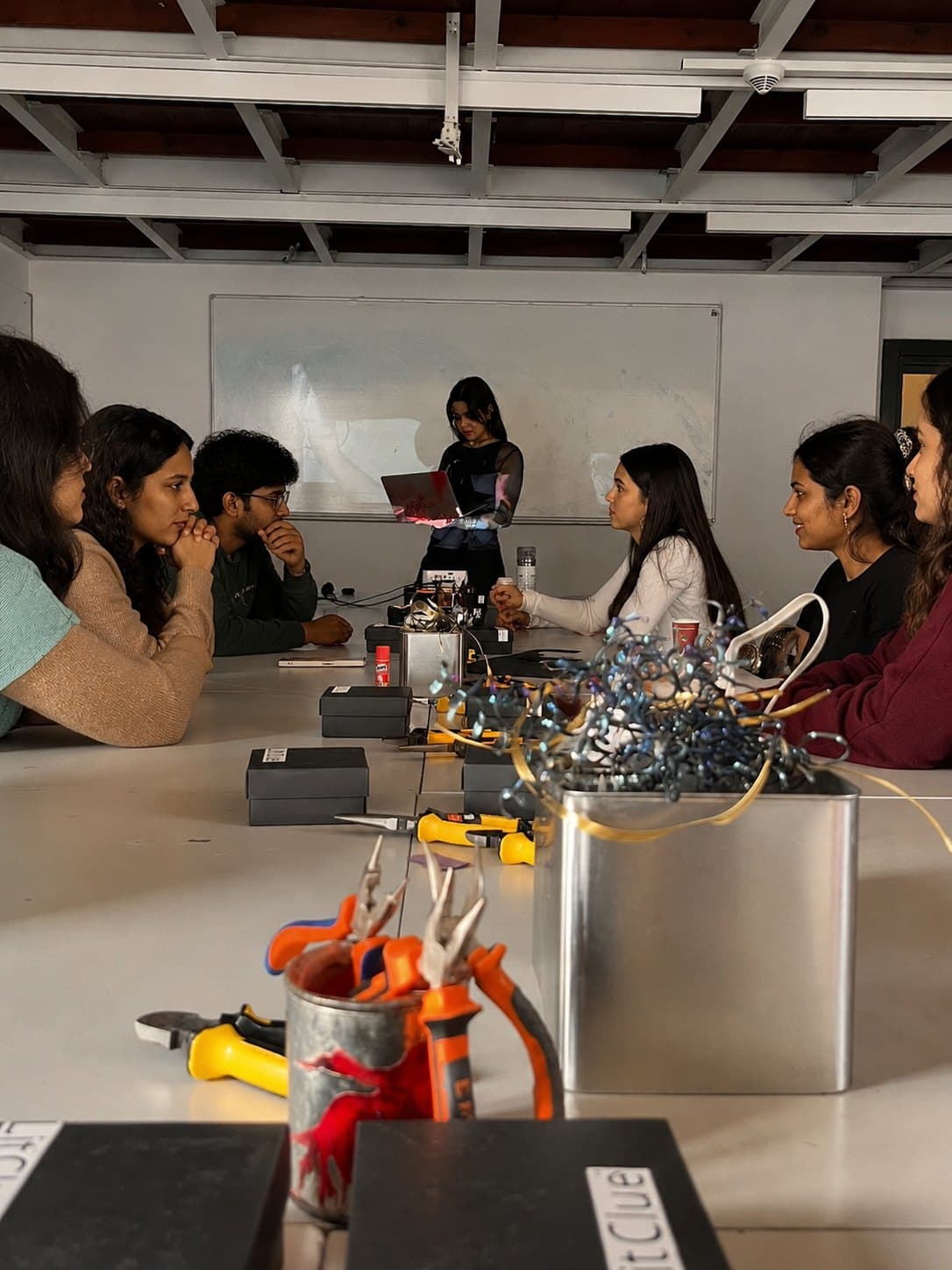 Students gathered around a workshop table with tools, components and a laptop